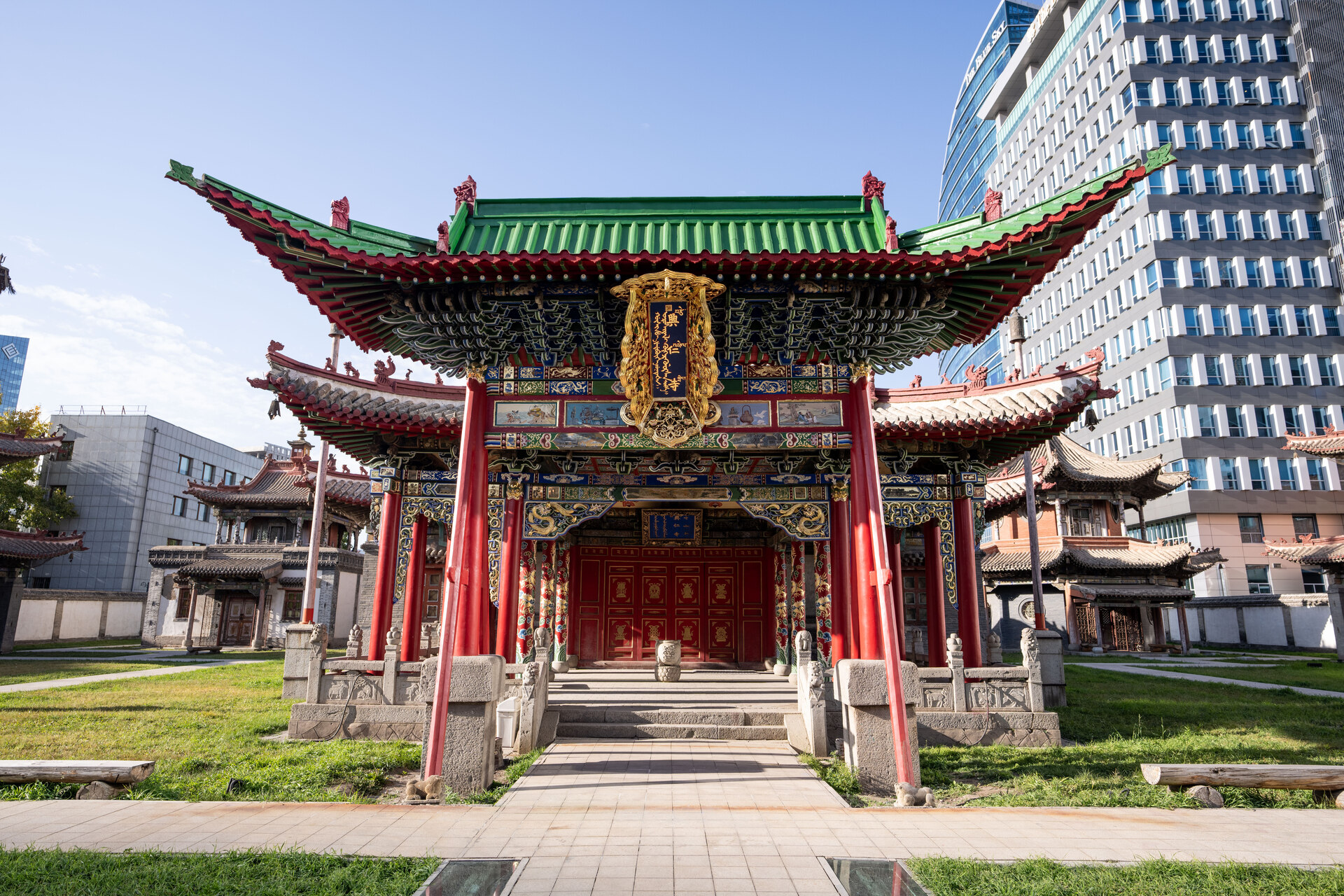 A view of the vibrant Main Temple at Choijin Lama Temple Museum in Ulaanbaatar, Mongolia, featuring ornate red pillars and a green roof.