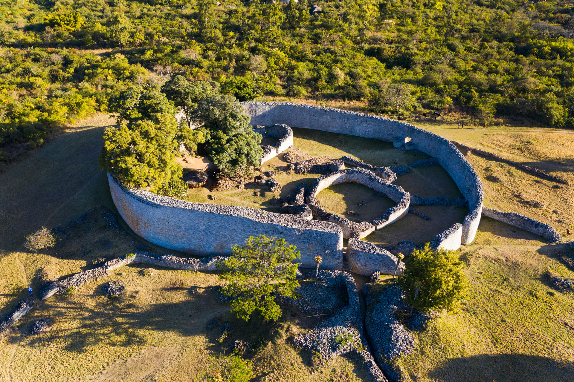 An aerial view of the stone ruins of Great Zimbabwe, surrounded by lush green landscape.