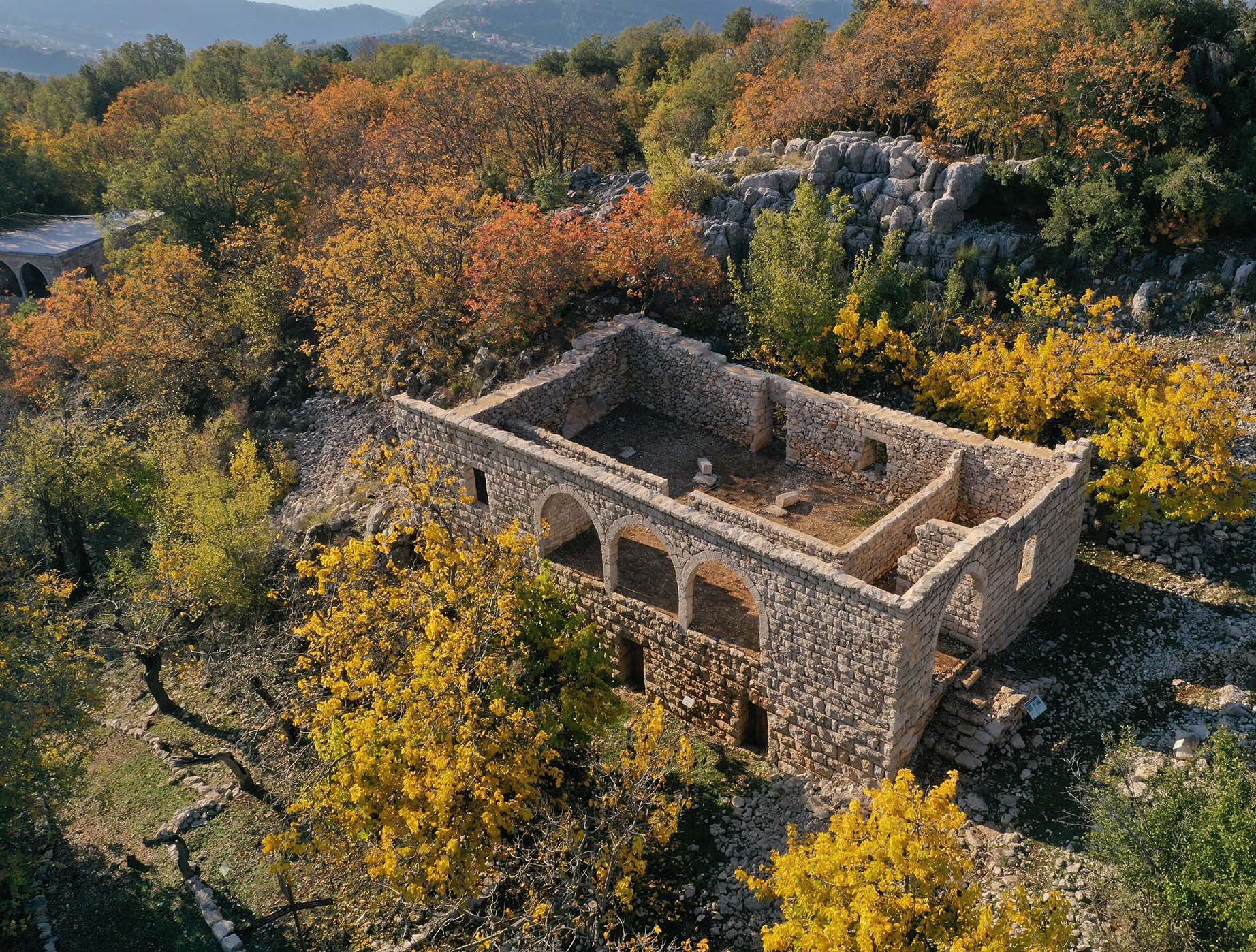 A rocky and verdant landscape with a two-story stone structure ruin.