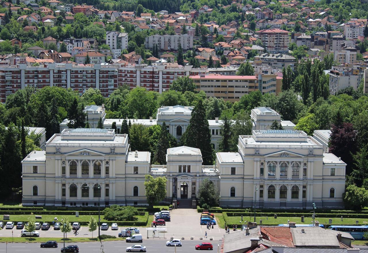 Aerial view of large, white neoclassical building with gardens